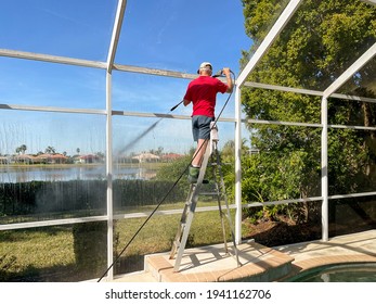 Handyman Cleaning Outdoor Screen Pool Cage Enclosure With Power Washer. Screened Swimming Pool Patio Maintenance And Screen Repair Service.
