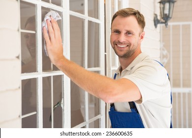 Handyman cleaning the window and smiling in a new house