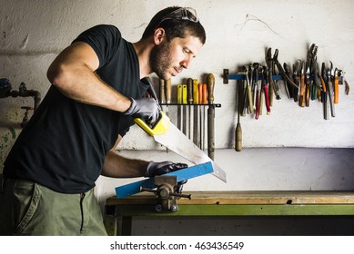 Handyman Cutting Wood With Hand Saw In The Garage