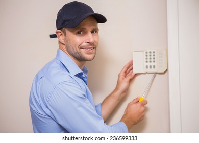 Handyman Fixing An Alarm System On The Wall