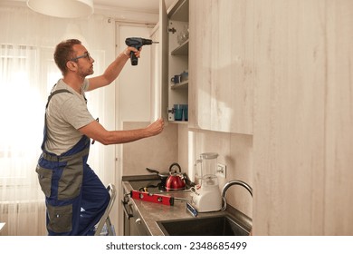 Handyman fixing kitchen cabinets in the apartment. - Powered by Shutterstock