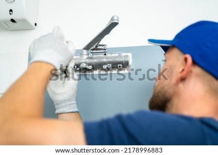 Handyman Installing And Fixing Automatic Door Closer. Maintenance And Service