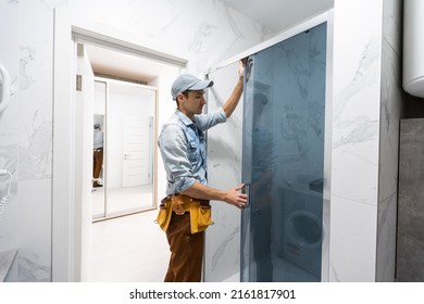 Handyman installing glass cabinet in bathroom. - Shutterstock ID 2161817901