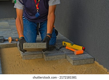 Handyman Paver Arranges Paving Stones. Construction Of The Pavement. Visible Paving Tools: Laser Level, Rubber Mallet, Slide Hammer And Chisel.