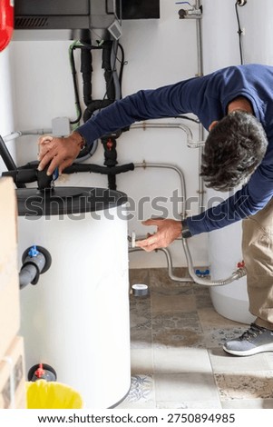 Handyman performing maintenance and installation work on a modern water heater or boiler system at home, ensuring efficient household plumbing and hot water supply