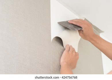 Handyman Putting Up Wallpaper On The Wall