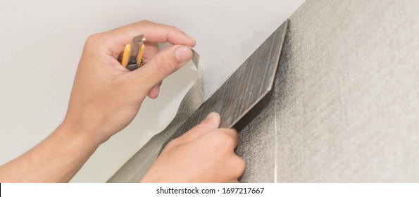 Handyman Putting Up Wallpaper On The White Walls,Maintenance Repair Works Renovation In The House, Restoration Or Installation Indoors. Banner Size 


