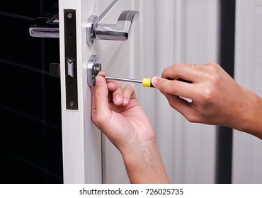 handyman repair the door lock in the room, Man fixing lock with screwdriver, Close-up of repairing door, professional locksmith installing or repairing a new deadbolt lock on a house