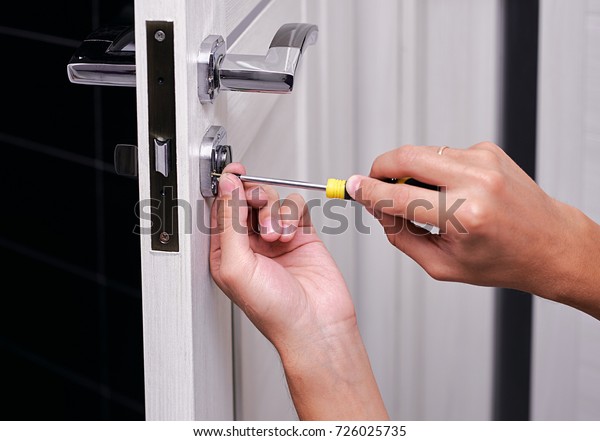 handyman repair\
the door lock in the room, Man fixing lock with screwdriver,\
Close-up of repairing door, professional locksmith installing or\
repairing a new deadbolt lock on a\
house