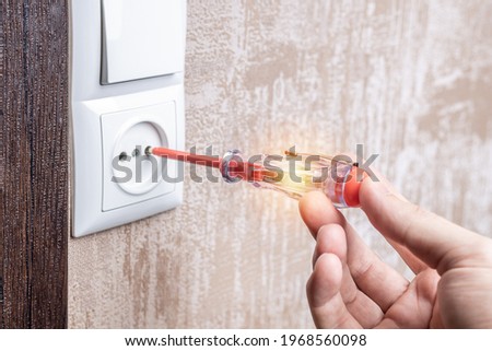 handyman repair wall outlet at apartment. worker using voltage electric tester to check outlet. electrician service concept.