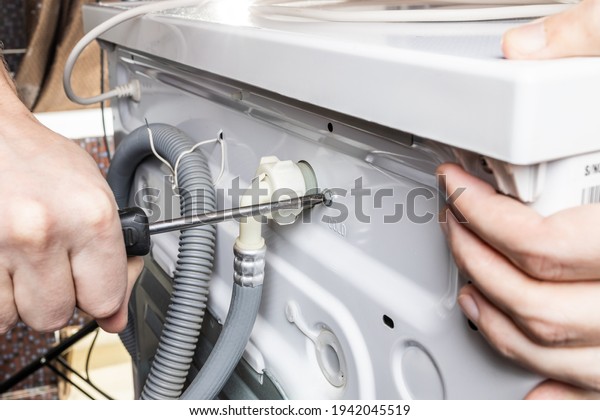 handyman repair\
washer at back side. washing machine repair service concept.\
connecting water supply to\
appliance.