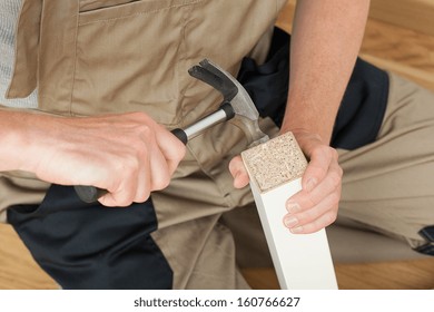 Handyman Repairing Broken Table Leg With A Hammer