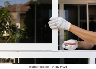 Handyman repairing the sliding window. Adjust a rail wheel and lock hook.
