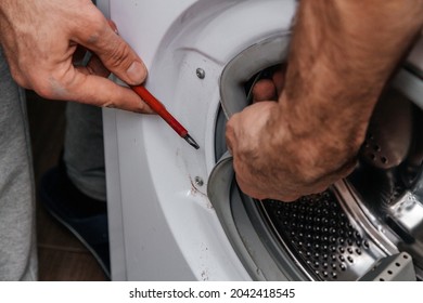 Handyman repairing a washing machine. The hands of a man repair a washing machine. Close-up