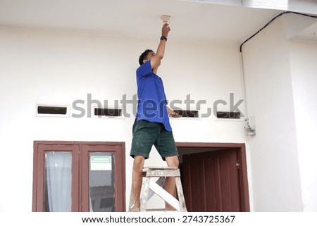 Handyman replacing light bulb on high porch ceiling