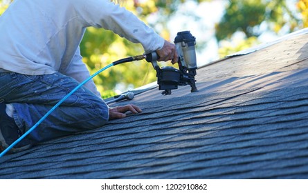 Handyman Using Nail Gun To Install Shingle To Repair Roof     