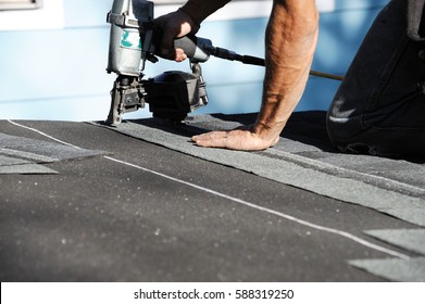 Handyman Using Nail Gun To Install Shingle To Repair Roof