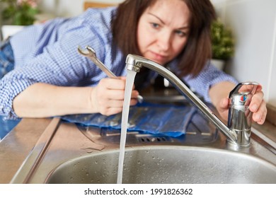 Handyman Woman Controls Water Flow At The Repaired Sink In The Kitchen