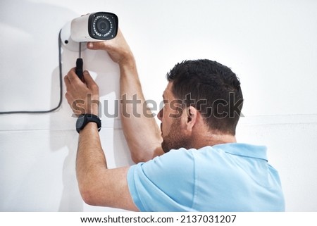 Handymen are always handy to have around. Shot of a mature man installing a security camera on a building.