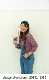 Handywoman Apprentice Holding Caulking Guns On White Background In Construction Equipment Tools Store. Females Carpenter Working In Carpentry Shop. DIY Woodworking Crafts And Hobbies Workshop.