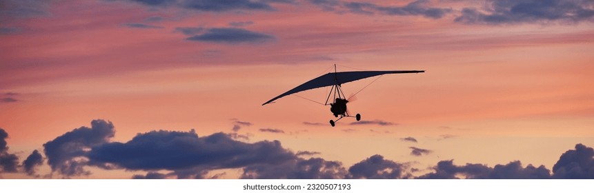 Hang glider on a motor on a summer evening against the backdrop of a sunset sky. Extreme sport. Banner, blank for an advertising layout with a place for writing - Powered by Shutterstock