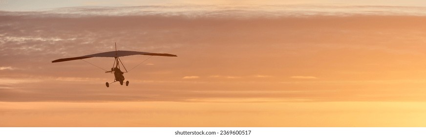 Hang glider on a motor on a summer evening against the backdrop of a sunset sky. Extreme sport. Banner, blank for an advertising layout with a place for writing - Powered by Shutterstock