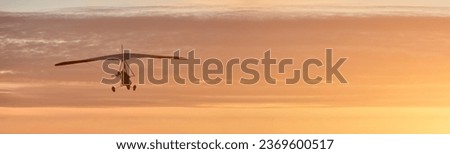 Hang glider on a motor on a summer evening against the backdrop of a sunset sky. Extreme sport. Banner, blank for an advertising layout with a place for writing
