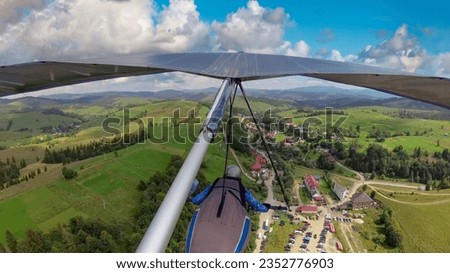 Hang glider pilot flying in the highlands. POV photo from onboard action camera