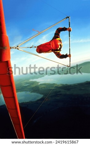 hang glider pilot with red hangglider and red helmet in a steep curve, also called knife flight, over Fuessen Allgaeu Bavaria Germany