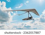 Hang glider pilot soar in the blue sky with clouds. Dream of flying come true.
