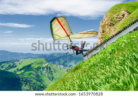 Hang glider pilots runs from steep slope high in the mountains. Diedamskopf, Austria. Extreme airborne sport.