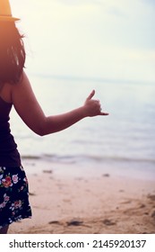 Hang Ten. Rearview Shot Of A Young Woman At The Beach Gesturing Hang Ten.