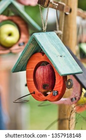 Hanged up wooden manger with apple for small birds. Care for animals and their protection.