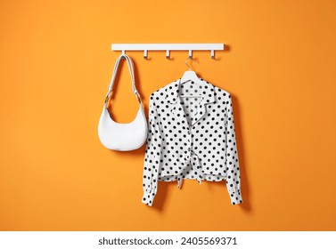 Hanger with polka dot shirt and bag on orange wall - Powered by Shutterstock