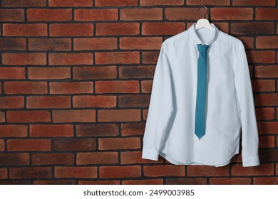 Hanger with white shirt and turquoise necktie on red brick wall, space for text - Powered by Shutterstock