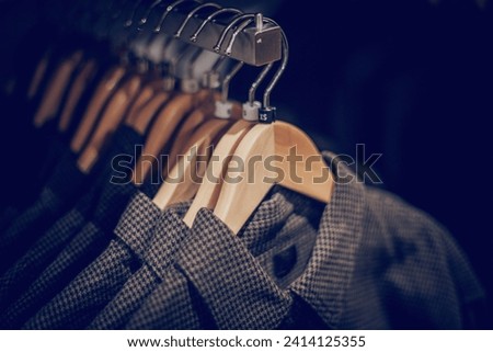 Hangers with clothes on the rail in the store. Shopping in store. Clothes on hangers in shop for sale. Blur background. Fashionable clothes in a boutique. Various clothing on market.
