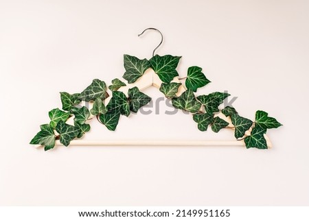 Hangers entwined with plants on background with copy space.Conscious and environmentally friendly consupmtion in shopping.Recycling or zero waste concept.Shopping,sale,promo.