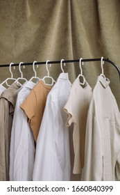 Hangers With Neutral Beige-colored Clothes On Rack On Green Velvet Background.