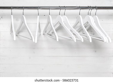 Hangers On The Rack Placed Sort Of Chaotically, All White With Black Hooks