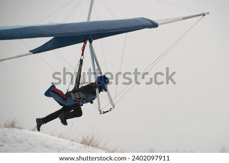Hangglider pilot runs very fast to get airborne from the hill. Dream of flying. Modern Icarus.