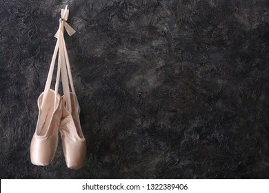 Hanging ballet shoes on dark wall