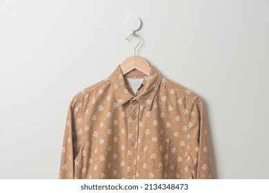 Hanging Beige Shirt With Wood Hanger On Wall