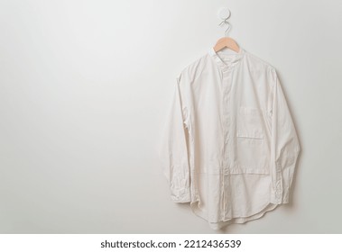 Hanging Beige Shirt With Wood Hanger On Wall