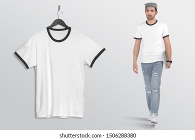 Hanging Black Plan Ringer T Shirt On Wall. Beside A Male Model Walking In Blue Denim Jeans Pant, Holding Laptop In His Hand, Wearing Grey Hat.