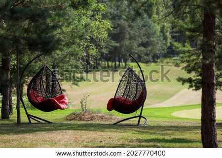 Hanging chair with a red plaid on a golf course. 
