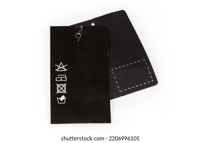 Hanging Clothes Tags In The Form Of The Black Carton Sheets With Holes, One Of Them With Pictured Clothing Care Symbols On A White Background
