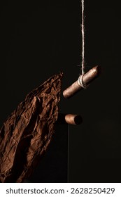 Hanging dried tobacco leaves and wooden cigar molds in a low-light setting for artisan processing and craftsmanship