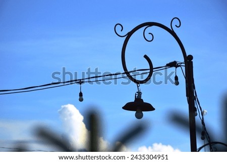 The hanging garden lamp with a classic style pole that appears installed in a yard with a bright blue sky in the morning