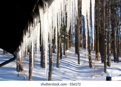 Hanging Icicles From An Alpine-style Ski Lodge With Wooded Snow Scene As Background