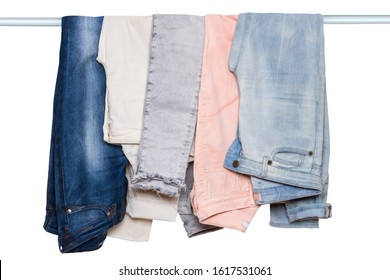 Hanging Jeans Isolated. Closeup Of Collection Of Five Female Various Denim Pants Or Colorful Trousers On A Clothes Rail Isolated On A White Background.Jeans Fashion.